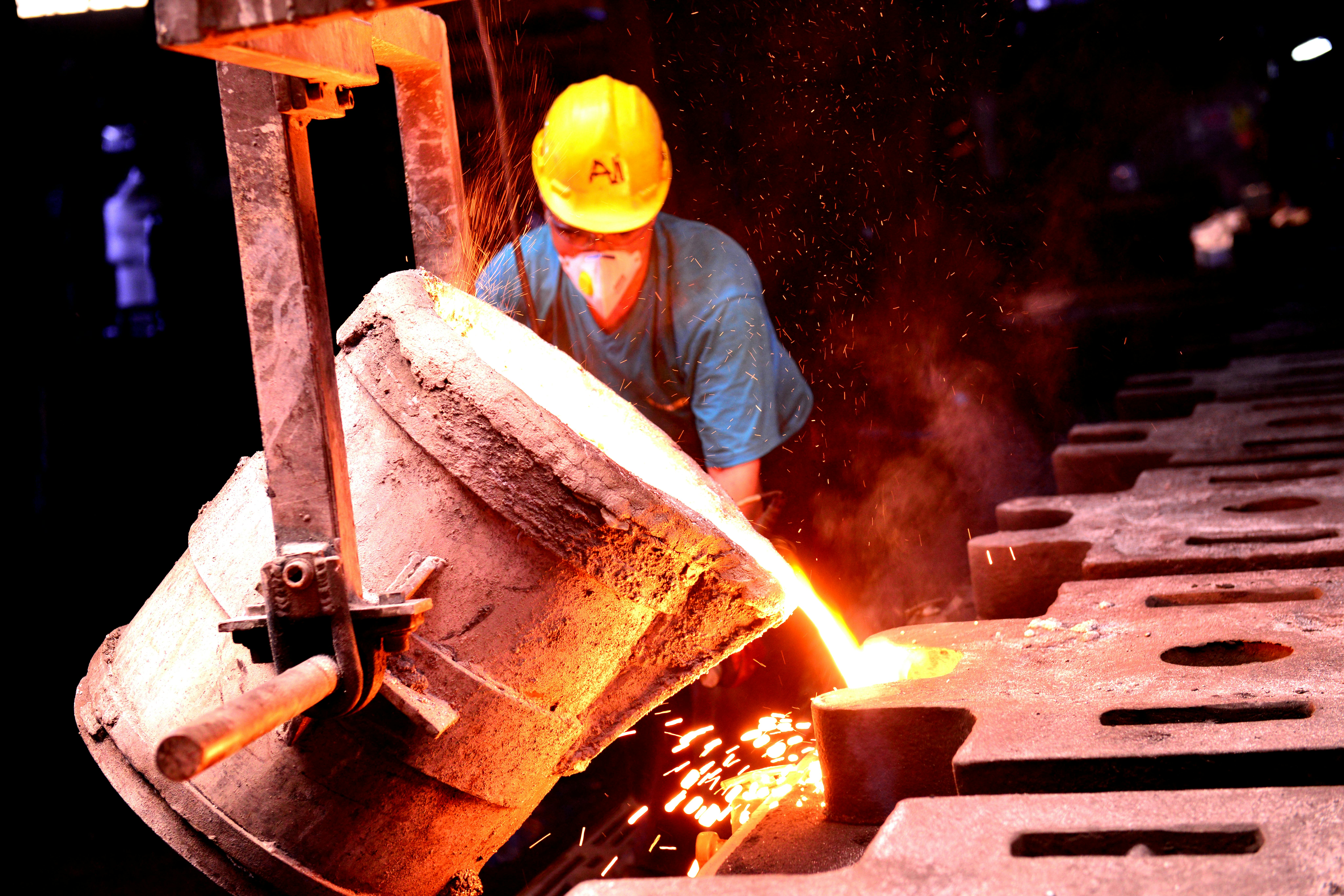 Industrial worker melting metal in foundry